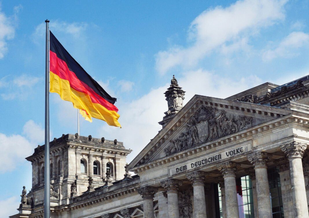 Drapeau allemand flottant devant un bâtiment historique en Allemagne.