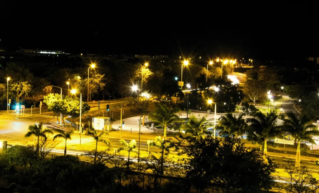 Ville illuminée la nuit avec des lampadaires et des palmiers.