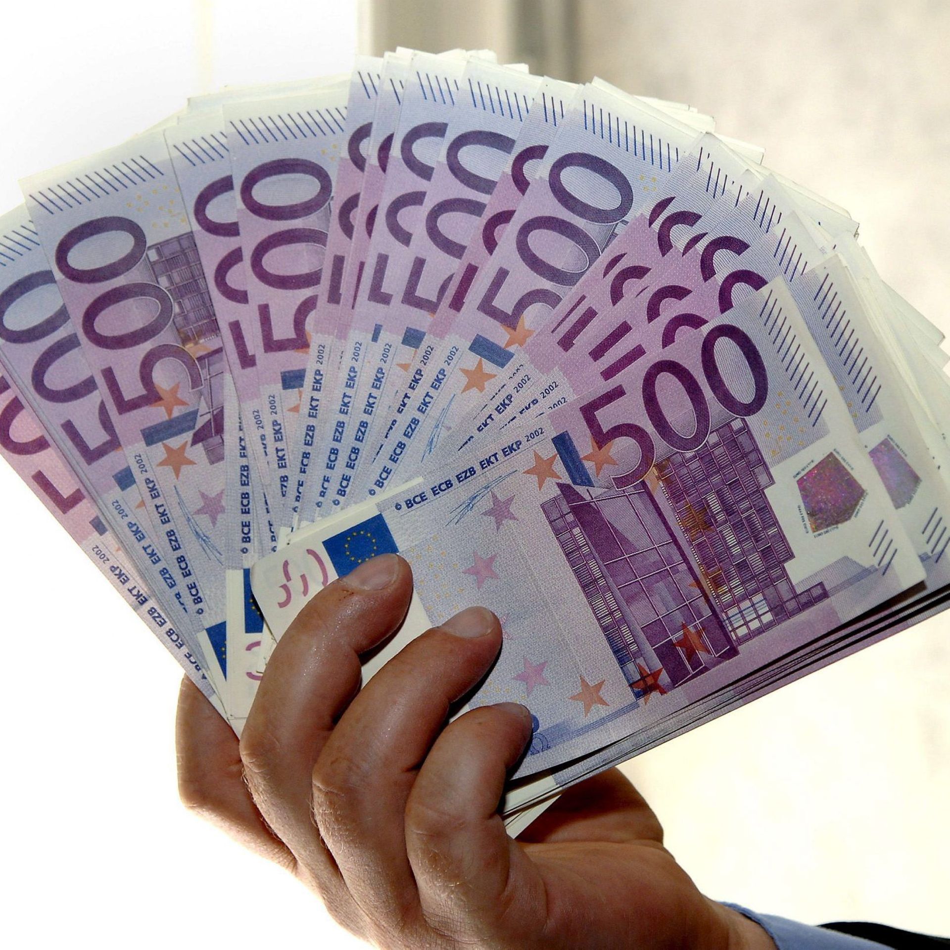 Main tenant des billets de 500 euros en éventail.