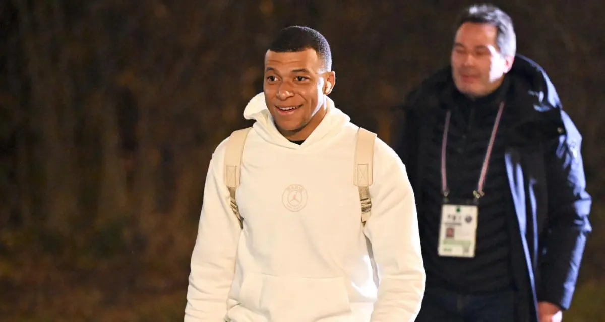 Kylian Mbappe souriant lors d'un déplacement nocturne.