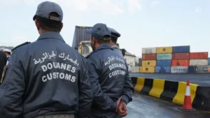 Douaniers algériens surveillant le port avec containers et barrières.