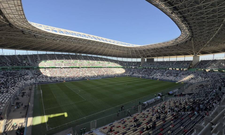 Stade de football vide avec un ciel bleu clair.