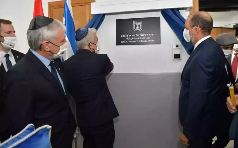 Hommes en costume et masques lors de l'inauguration d'un bureau de liaison.