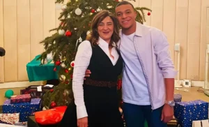 Jeune homme et femme souriants devant un sapin de Noël décoré.