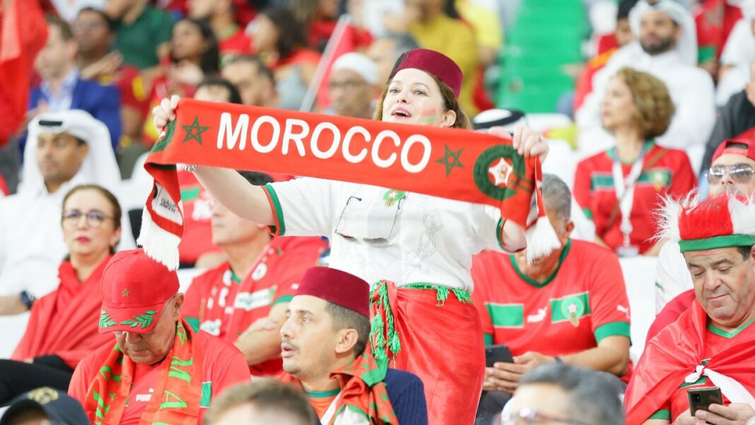 Supporters marocains en tenue traditionnelle et avec drapeau lors d'un match de football.