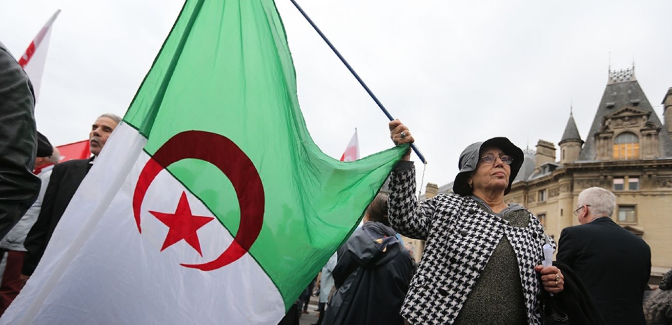 Femme tenant un drapeau algérien lors d'une manifestation.