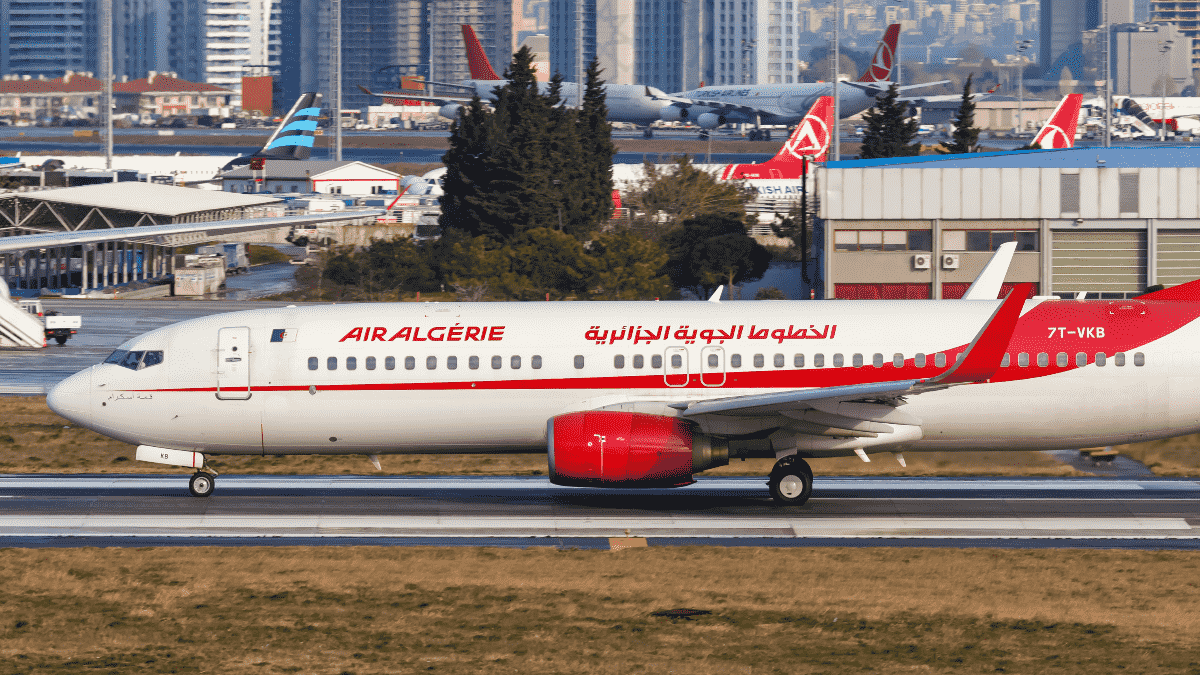 Avion Air Algérie sur la piste de l'aéroport avec la ville en arrière-plan.
