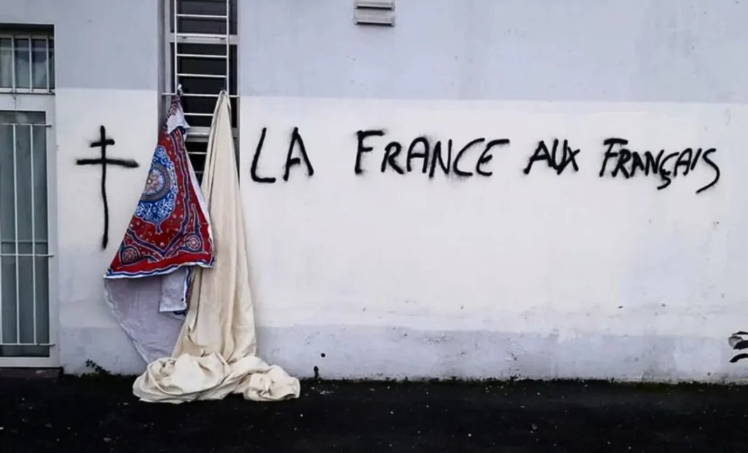 Graffiti avec texte "La France aux Français" sur un mur blanc.