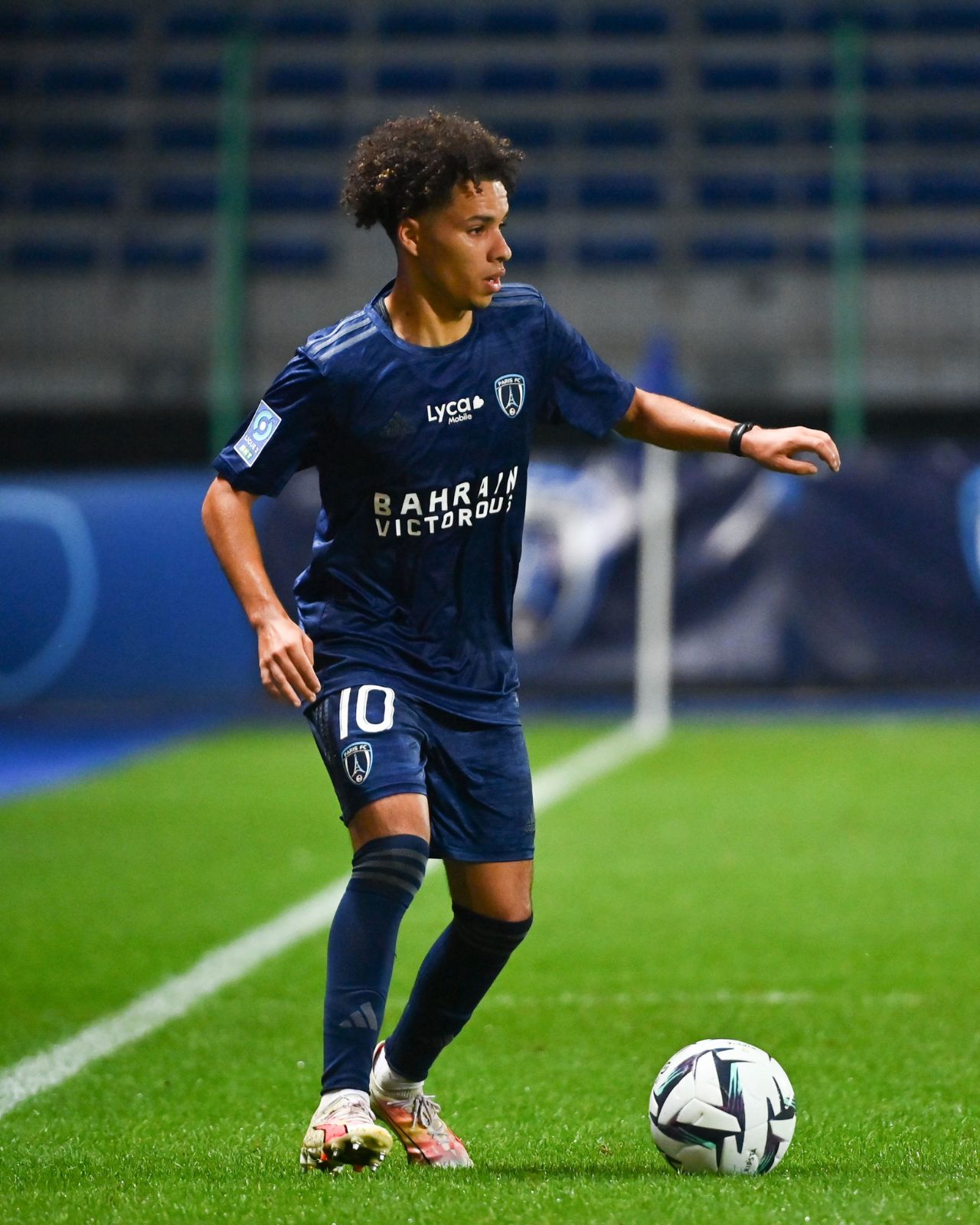 Jeune joueuse de football en pleine action sur le terrain.