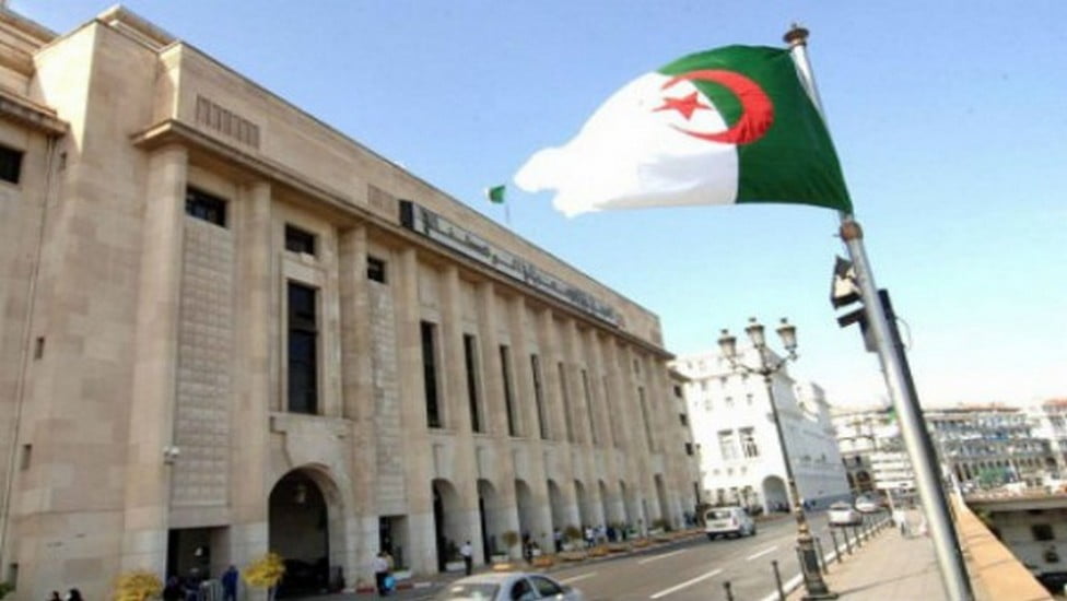 Drapeau algérien flottant devant un bâtiment officiel à Alger.