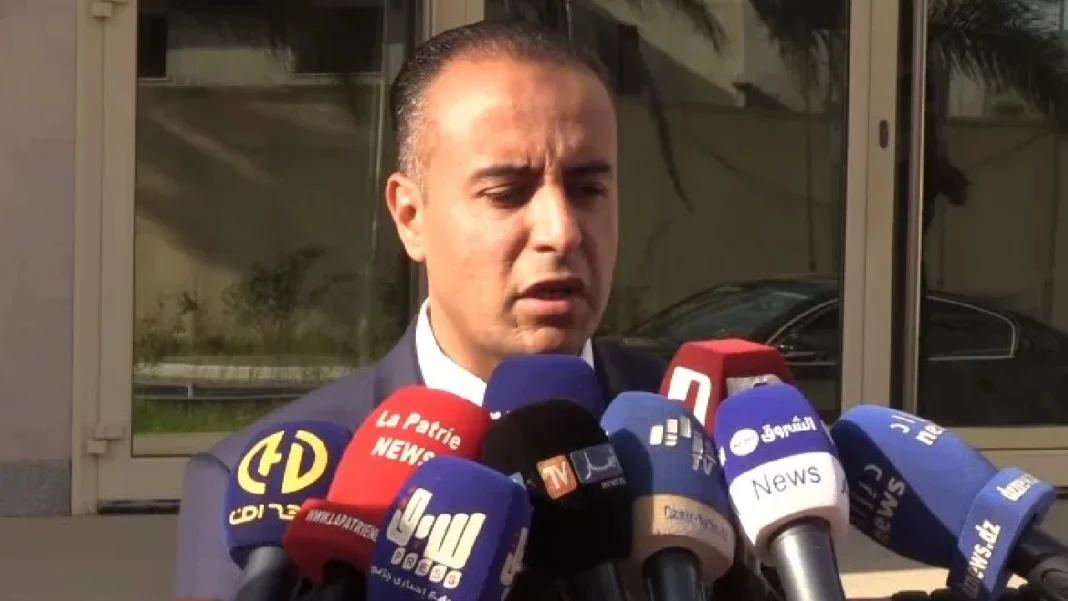 Walid Sadi parlant à la presse avec plusieurs microphones.
