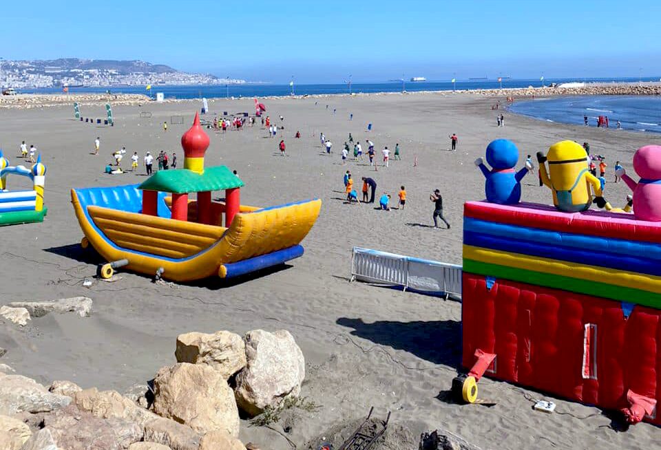Plage en Algérie avec structures gonflables colorées pour enfants.