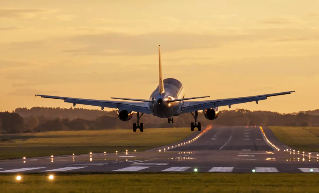 Avion en approche pour atterrir sur la piste d'aéroport au coucher du soleil.