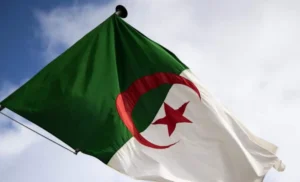 Drapeau algérien flottant dans le ciel avec nuages.