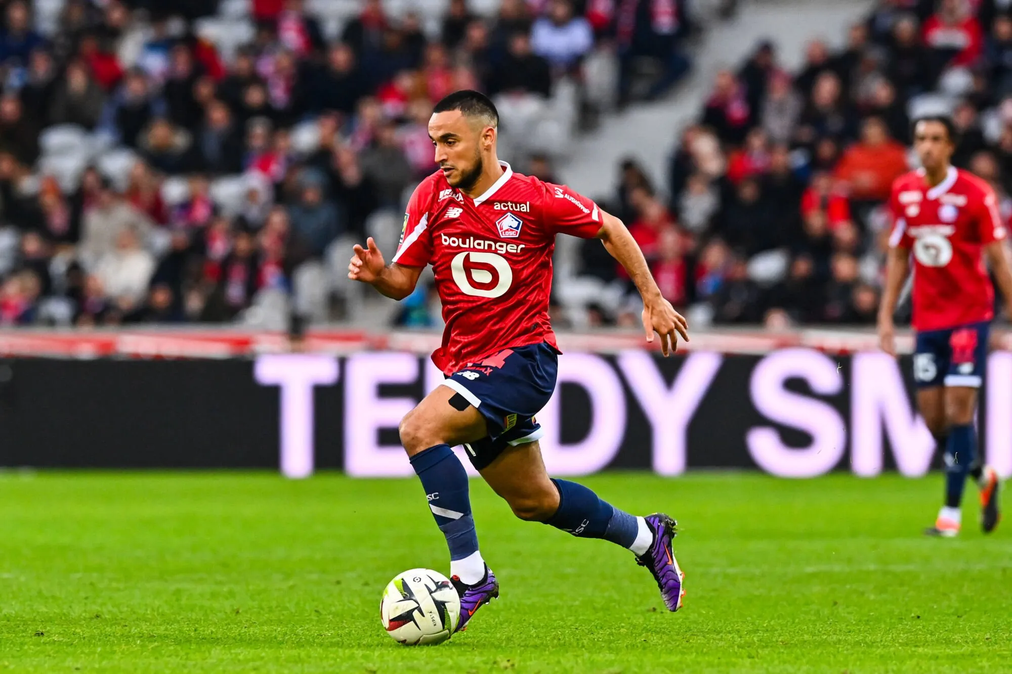 Footballeur en mouvement avec le ballon sur le terrain.