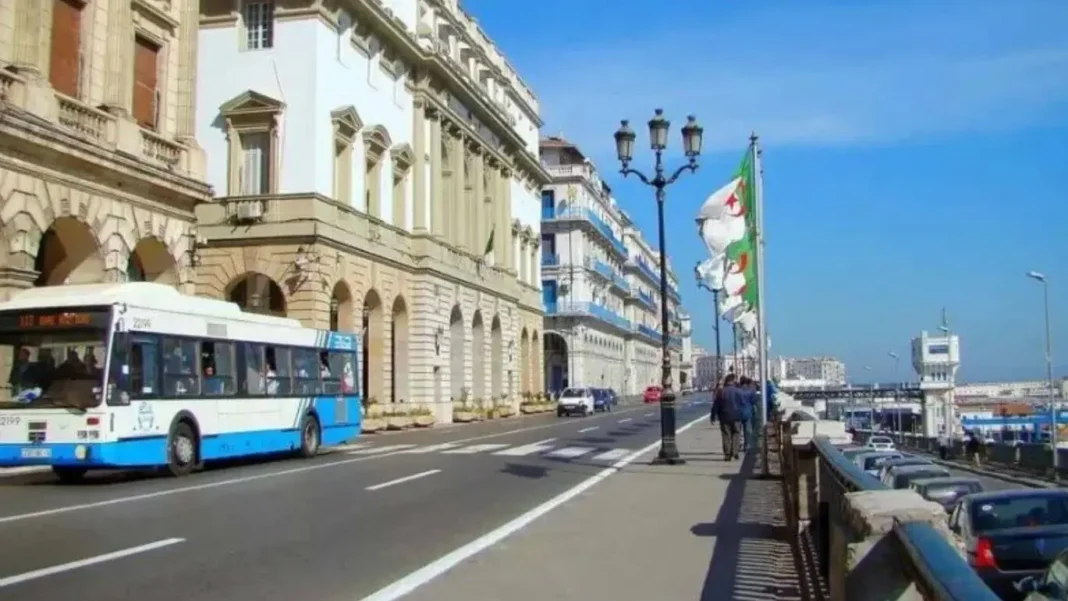 Promenade en bord de mer à Alger avec bus et bâtiments historiques.