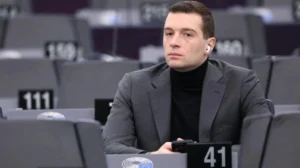 Jordan Bardella assis seul dans une salle de réunion du Parlement européen.