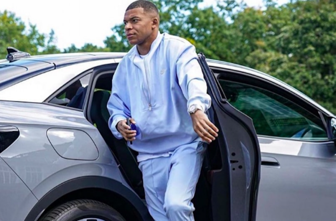 Kylian Mbappé sort d'une voiture avec un sac à dos.