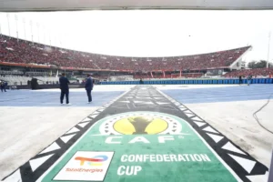 C'est terminé! La CAF décide enfin du sort de l'USM Alger Vue du terrain de football avec logo de la CAF et stade rempli en arrière-plan.