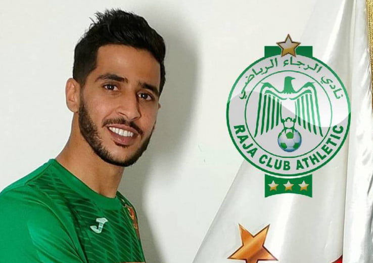 Raouf Benguit en maillot vert devant le logo du Raja Casablanca.