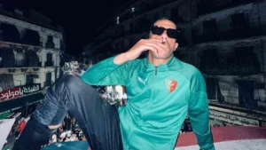 Le MCA sème la panique en Angleterre! Une célébration du club algérien tourne au vinaigre Supporter du club algérien MCA portant maillot vert et lunettes de soleil.