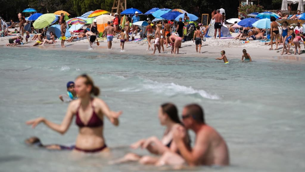 Plage animée avec parasols colorés et baigneurs.