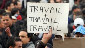 Maroc : le chômage chez les jeunes a atteint un niveau jamais enregistré. Retour sur les chiffres alarmants... Groupe de jeunes manifestants avec une pancarte 'Travail + Travail'.