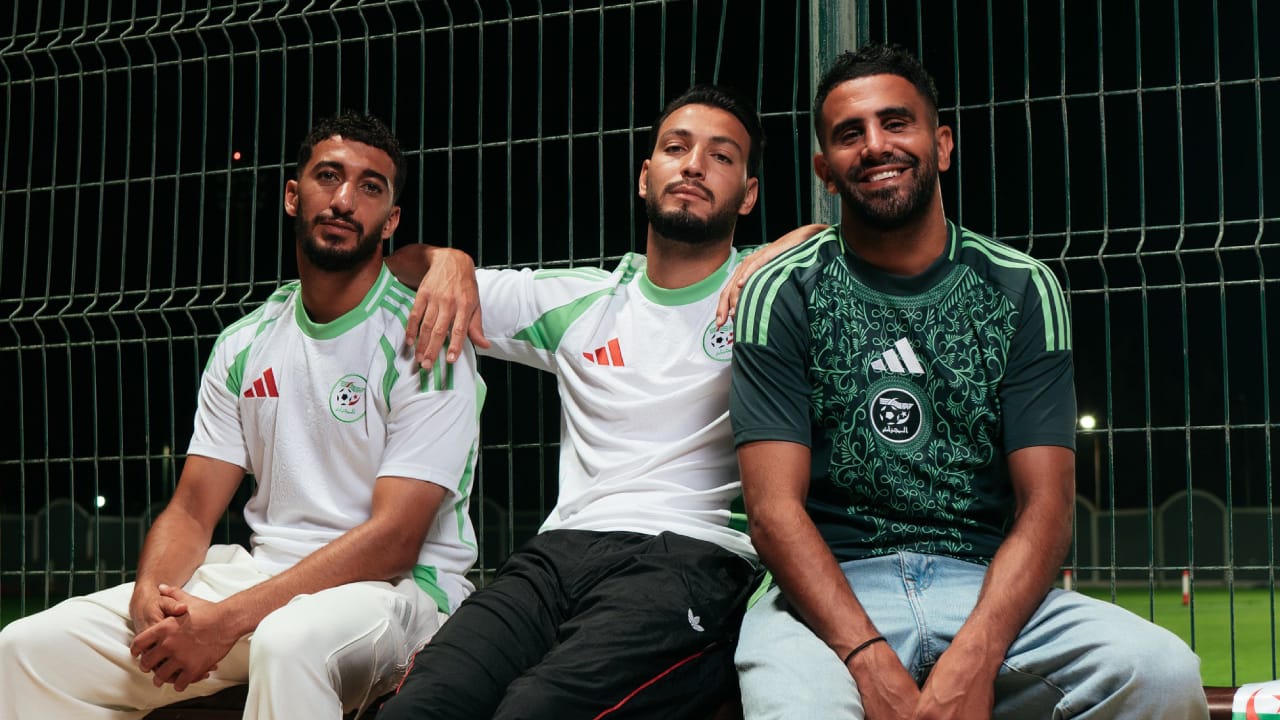 Trois joueurs algériens en maillots verts et blancs, assis sur un banc de football.