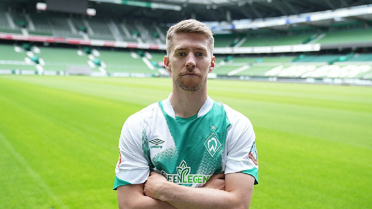 Mitchell Weiser en maillot de football sur le terrain d'un stade vide.