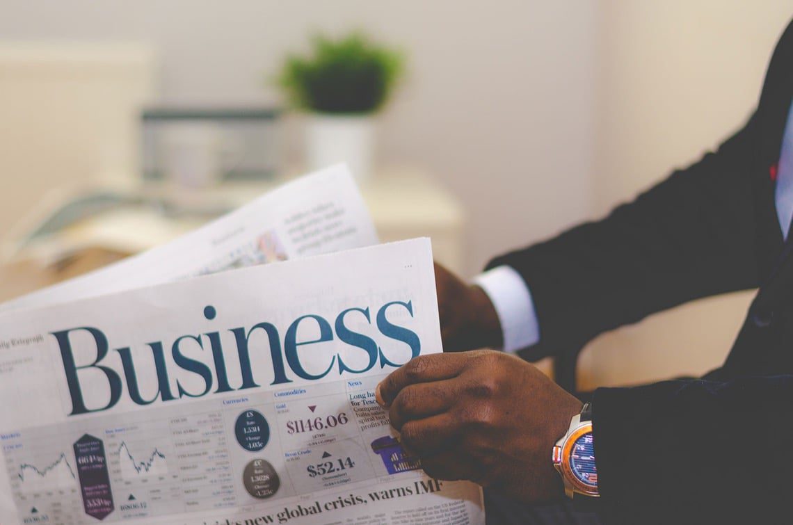 Homme en costume lisant un journal économique "Business".