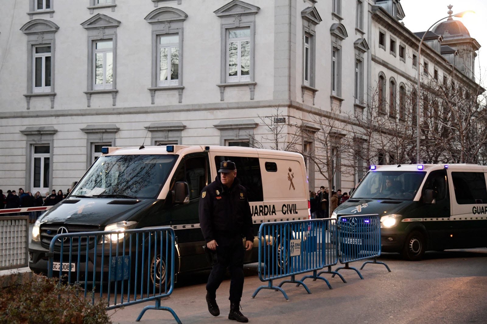 Véhicules de la Guardia Civil avec barrière de sécurité devant un bâtiment officiel.