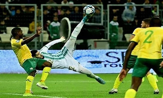 Joueur en action effectuant une plongeon pour arrêter le ballon lors d'un match de football.