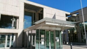 Quelle audace! Un sans-papiers algérien sous OQTF agresse un policier. La sentence est sans appel... Bâtiment moderne avec entrée en verre et structure en béton.