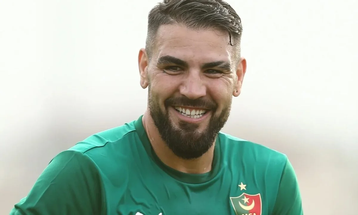 La mauvaise nouvelle d'Andy Delort frappe MC Alger ! Andy Delort souriant en maillot vert du MCA lors d'un match.