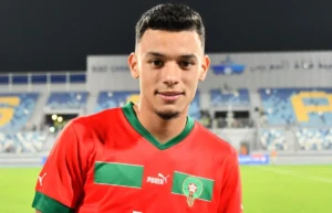 Jeune joueur marocain de football en tenue rouge sur le terrain.