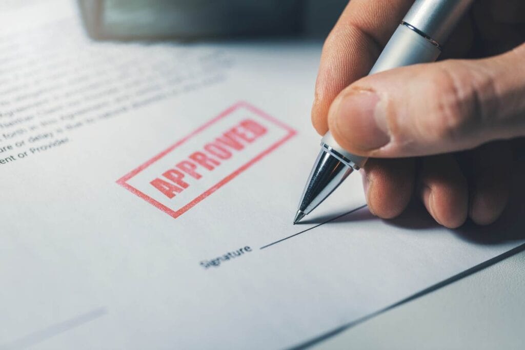 Signature manuscrite sur un document avec tampon approuvé.
