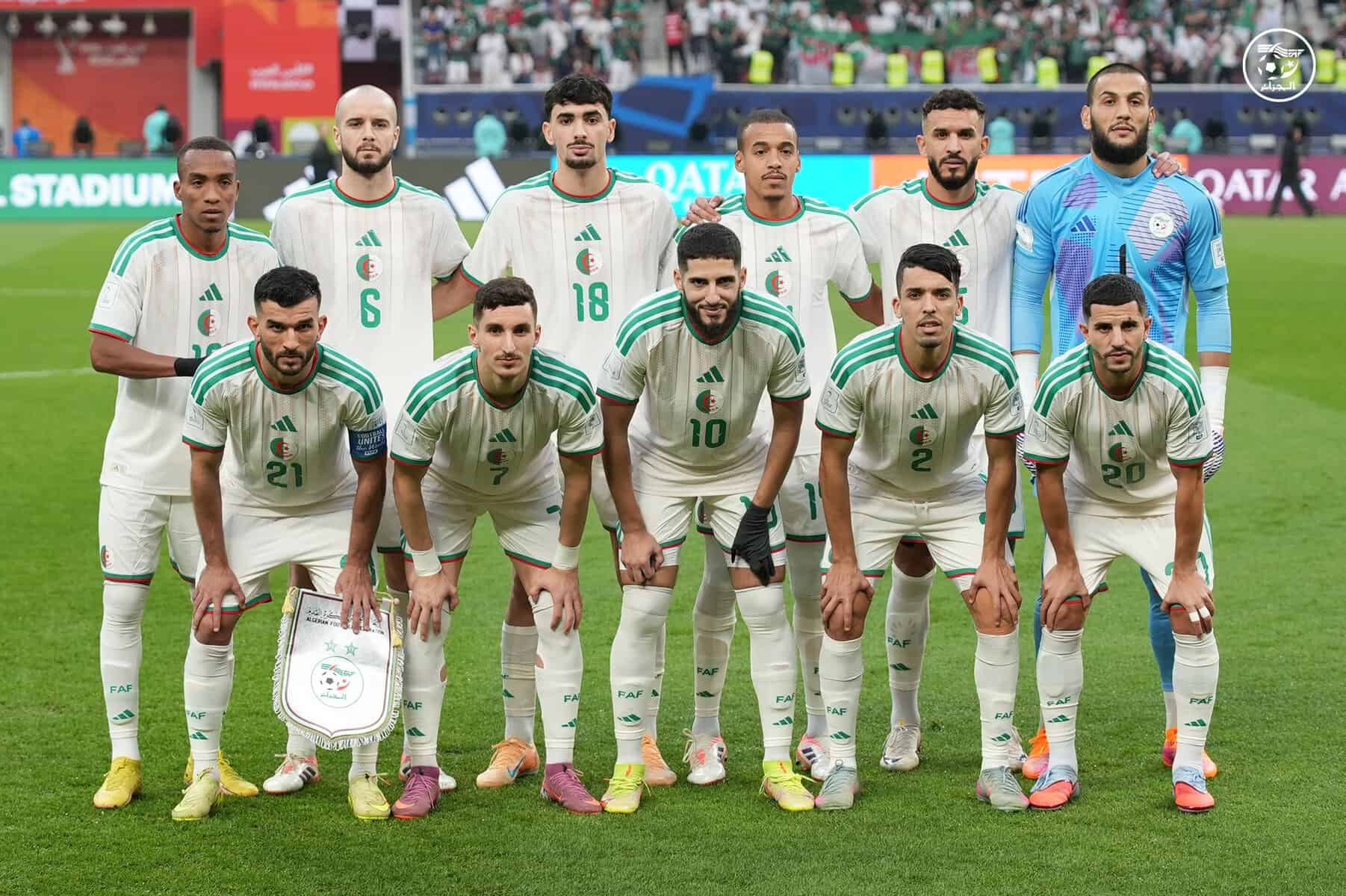 Groupe de joueurs de football algériens en tenue officielle sur le terrain.