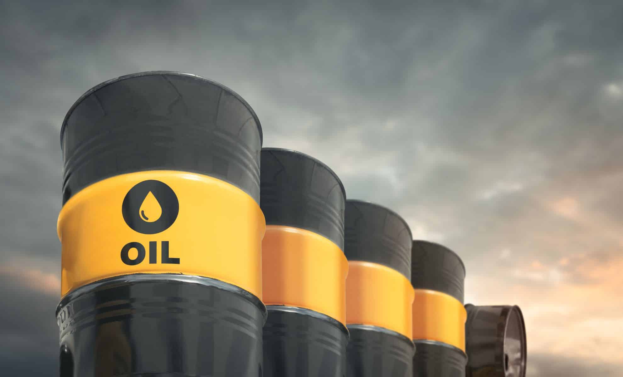 Barils de pétrole avec étiquette 'OIL' sous un ciel nuageux.