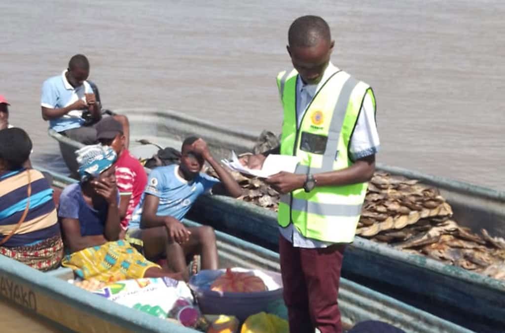 Agent de migration vérifiant des migrants dans un bateau sur le fleuve.