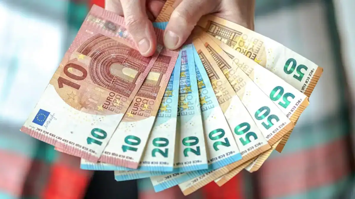 Main tenant des billets d'euros de différentes valeurs.
