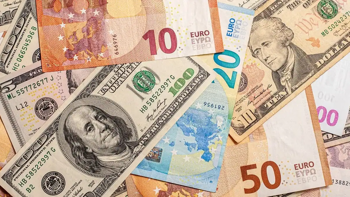 Billets en euros et dollars sur fond blanc.