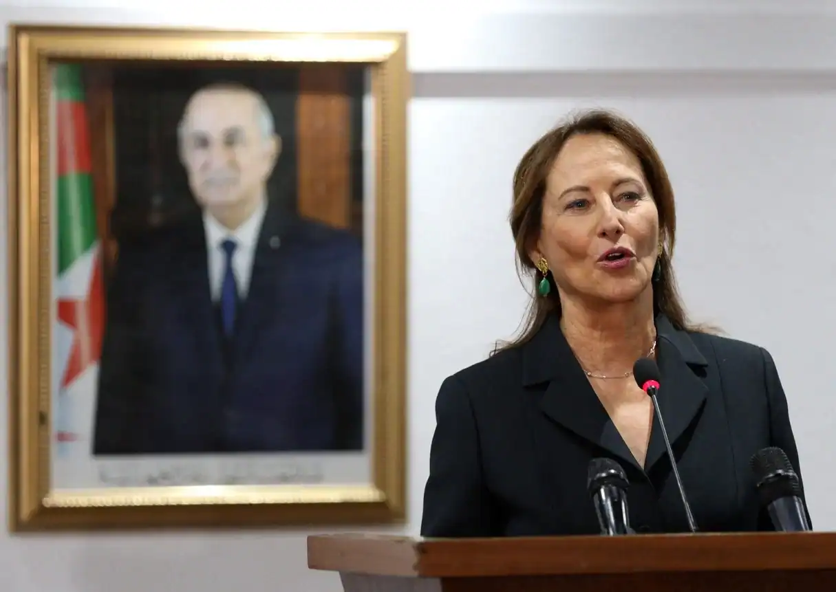 Ségolène Royal lors d'une conférence à Alger avec portrait en arrière-plan.