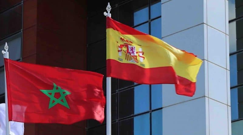 Drapeaux du Maroc et de l'Espagne flottant devant un bâtiment moderne.