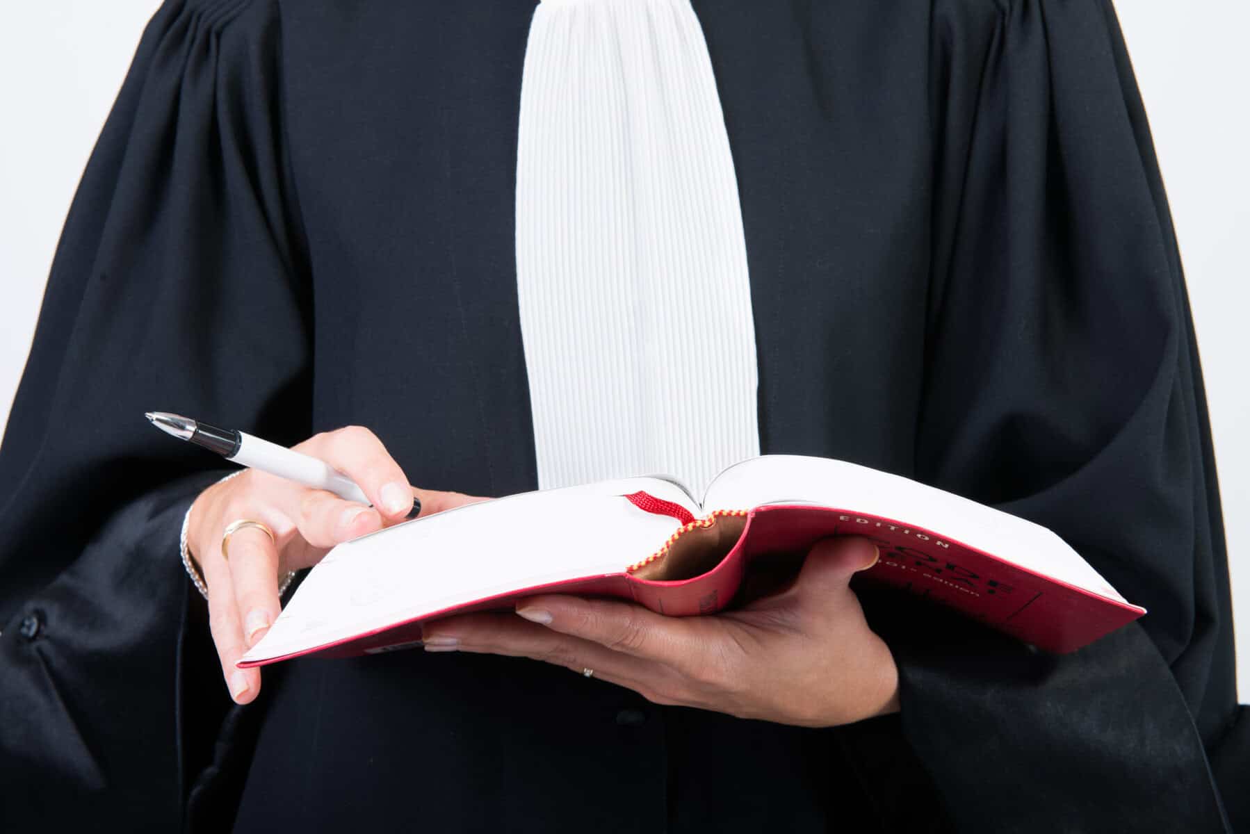 Juge en robe noire tenant un livre lors d'une audience judiciaire.