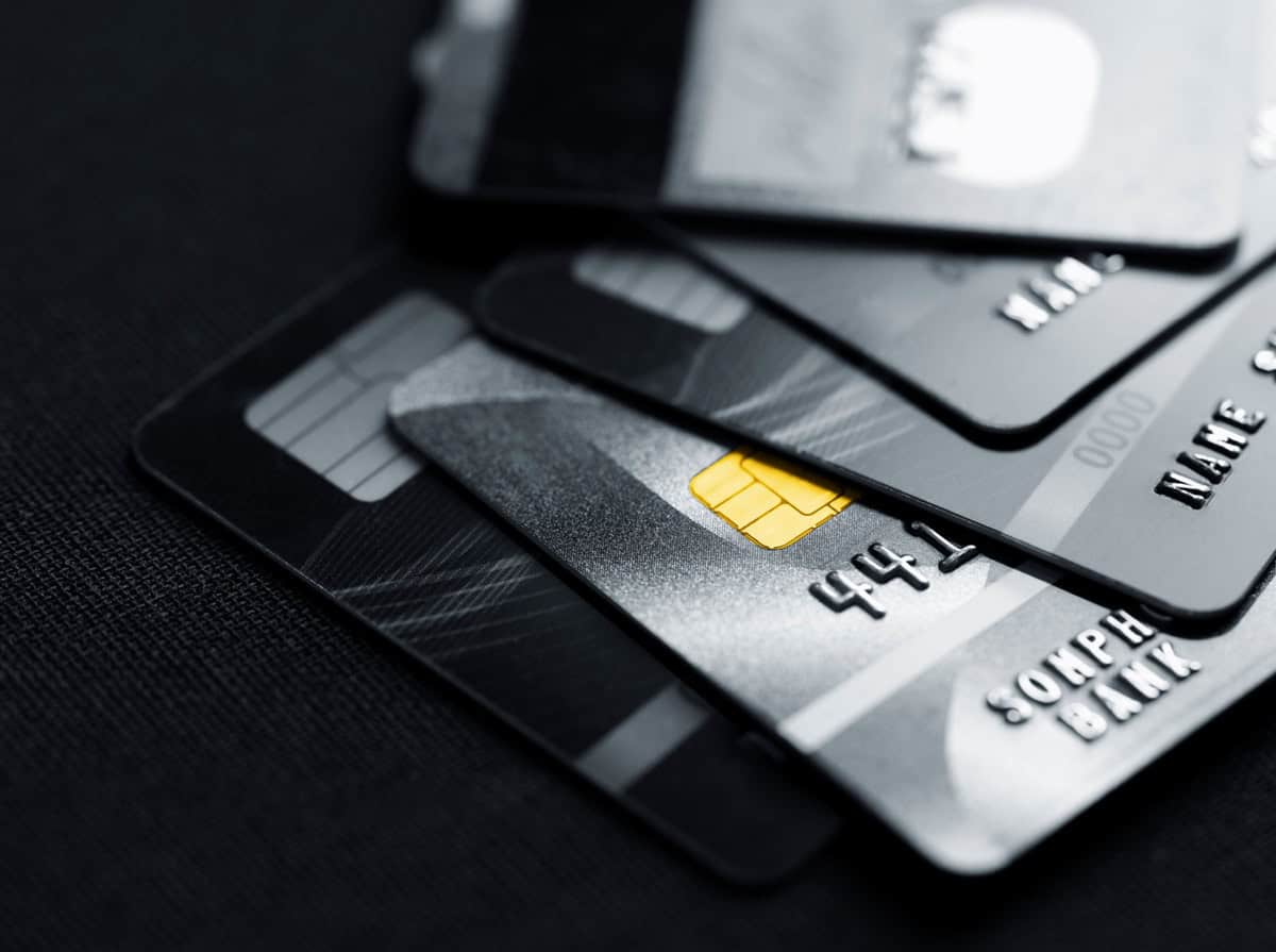 Procès à Londres : Un Algérien accusé d'un vol colossal Cartes de crédit empilées avec une pièce d'identité sur fond noir.