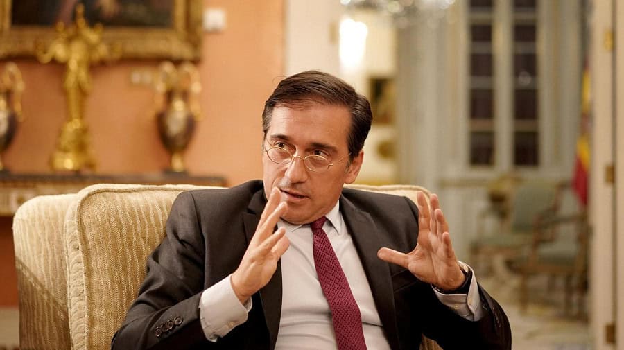Homme en costume parlant lors d'une réunion ou interview.