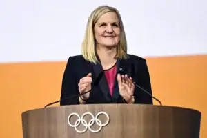 Imane Khelif à l'épreuve, parlant devant un podium olympique.