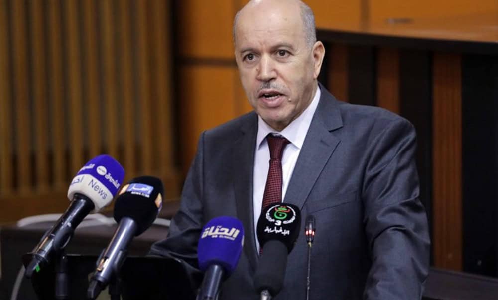 Homme en costume parlant lors d'une conférence de presse en Algérie.