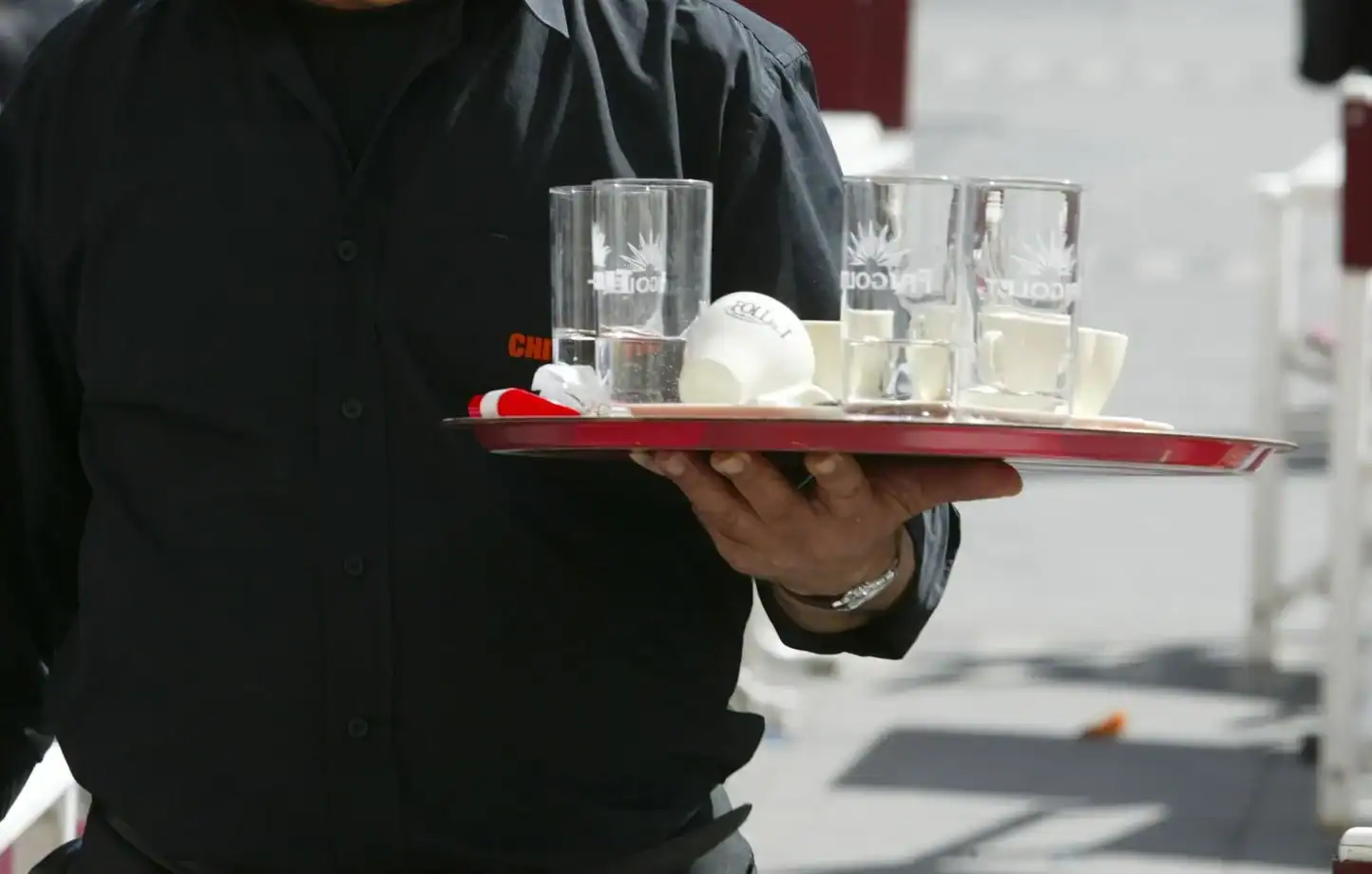 Serveur portant un plateau avec verres et balles de tennis.