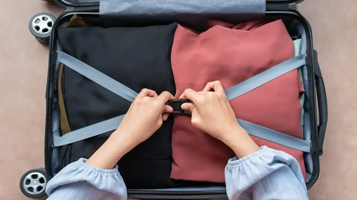Valise ouverte avec vêtements pliés et roulettes visibles.